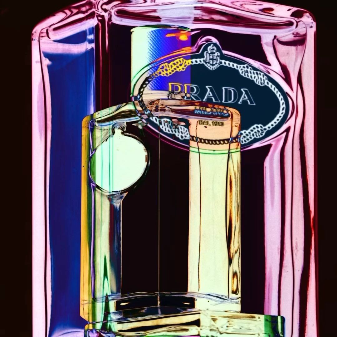 Close-up of a Prada perfume bottle, showcasing its branding and unique lighting with vibrant colors, creating a high-contrast and artistic image.