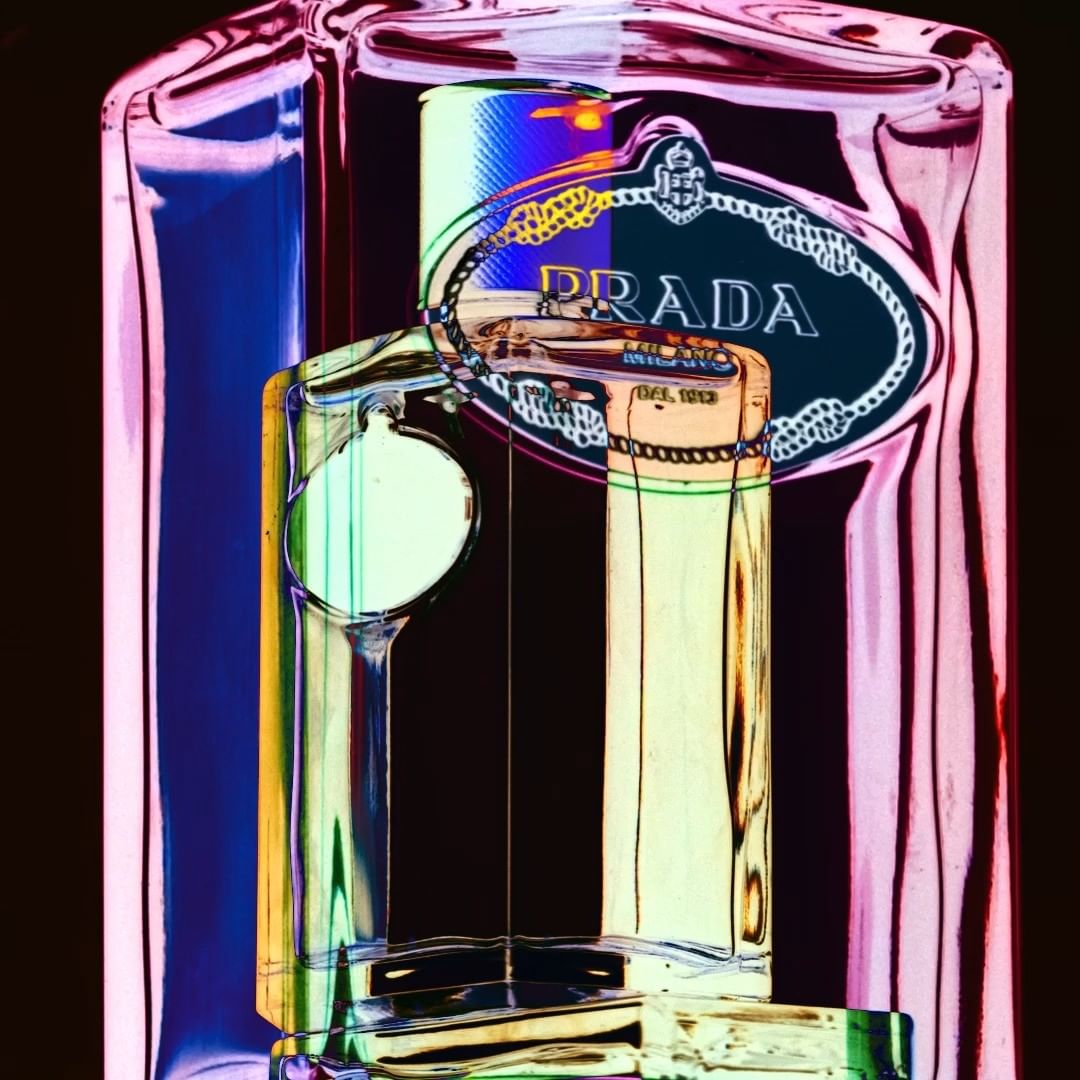 Close-up studio shot of a semi-transparent Prada fragrance bottle with colorful lighting, showcasing its modern design and luxury brand.