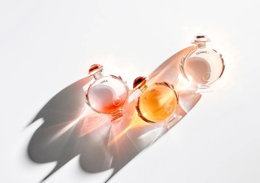 Three Olympea perfume bottles are arranged on a white surface, casting a shadow, product shot, beauty advertisement, simple elegant presentation.