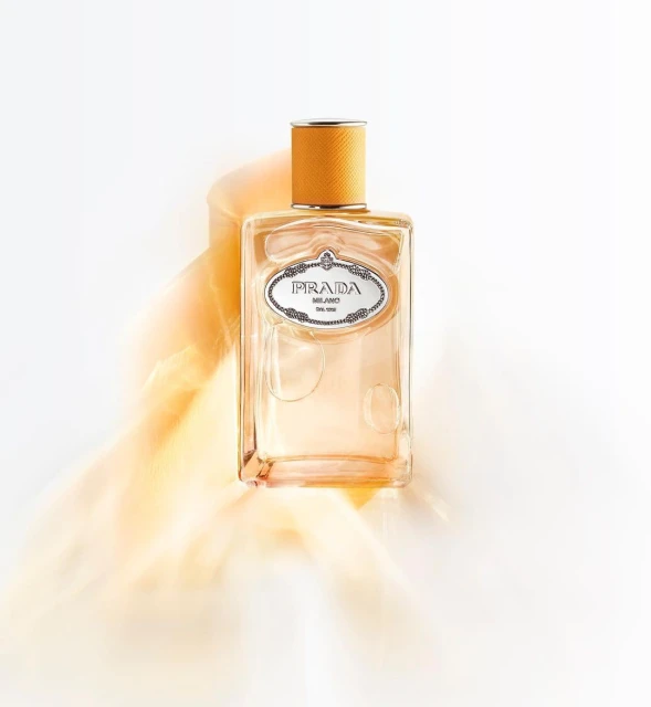 Prada perfume bottle on a white surface with orange smoke, showcasing a clean design and warm color palette in a studio setting.