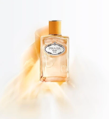 Prada perfume bottle on a white surface with orange smoke, showcasing a clean design and warm color palette in a studio setting.