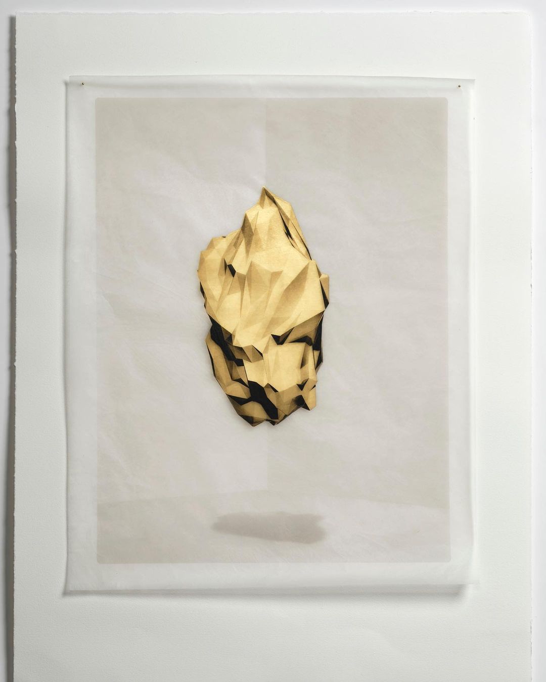 Geometric abstract art of a gold crumpled paper shape against a white background in a white frame under neutral studio lighting.