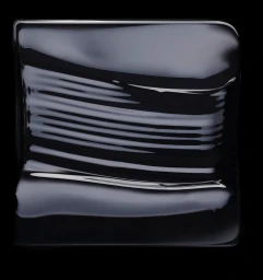 Close-up abstract photograph of glossy black liquid surface with smooth ripples on black background