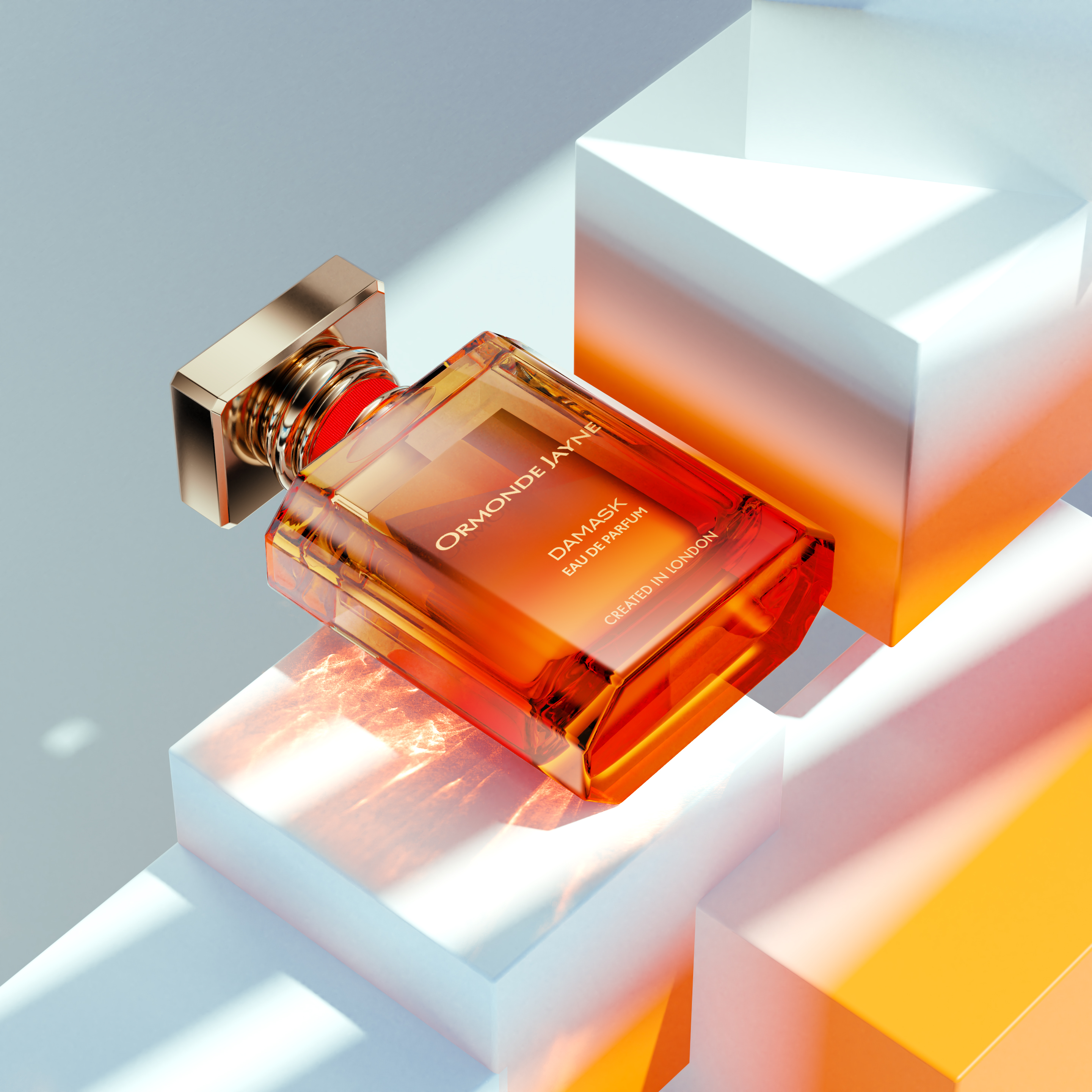 Product shot of amber Ormond Jayne Damask Eau de Parfum glass bottle on white cubic platforms, studio lighting, for beauty advertising.