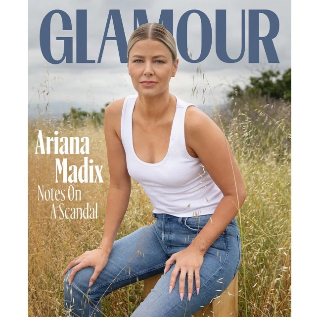 Glamour magazine cover featuring a woman sitting in a field, wearing a white tank top and blue jeans, with the magazine logo at the top.