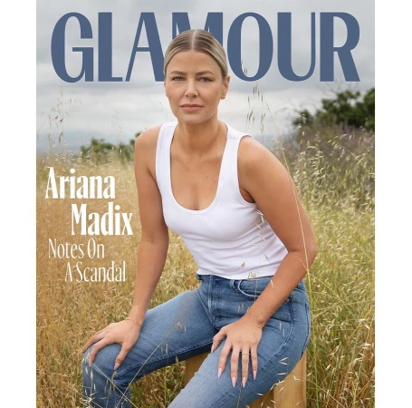 Glamour magazine cover featuring a woman sitting in a field, wearing a white tank top and blue jeans, with the magazine logo at the top.
