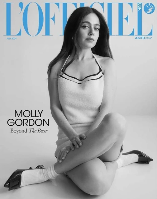 Molly Gordon poses for a black and white magazine cover, sitting cross-legged in a white dress, with 'L'Officiel USA' text visible.