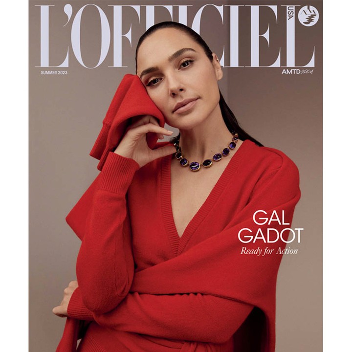 Gal Gadot on L'Officiel USA cover, Summer 2023. She wears a red V-neck sweater and a purple gemstone necklace in a neutral studio setting.