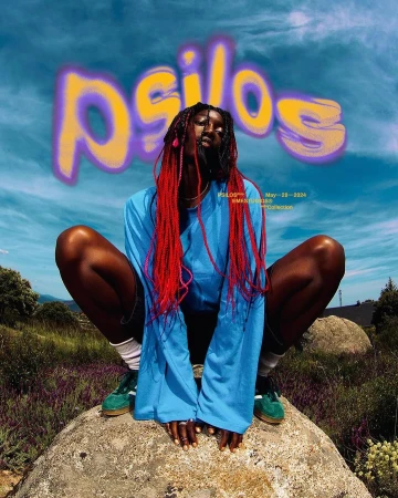Portrait of a Black woman with red braids posing on a rock outdoors, wearing a long-sleeved blue shirt and green shoes against a cloudy sky.