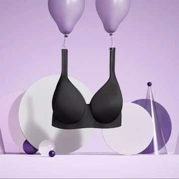 Black bra suspended by two lavender balloons against a purple set-dressed studio background with geometric shapes