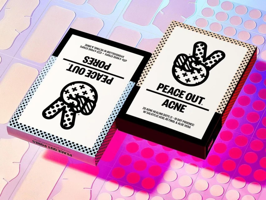 Two skincare boxes, Peace Out Acne and Peace Out Pores, are displayed on a pink and holographic surface with acne treatment patches.