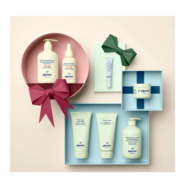 Arrangement of Pipette brand skincare products in original packaging placed in gift boxes and circle, with paper bow decorations.