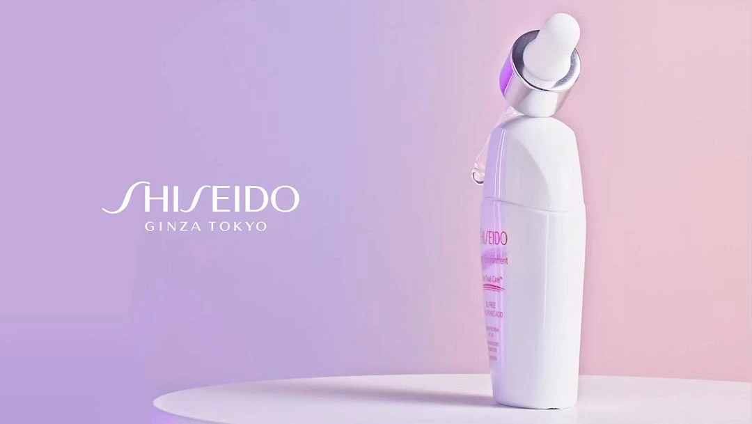 Shiseido Ginza Tokyo skincare product bottle on a white table, with a dropper applicator and a soft purple gradient background.