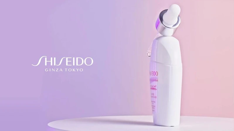 Shiseido Ginza Tokyo skincare product bottle on a white table, with a dropper applicator and a soft purple gradient background.