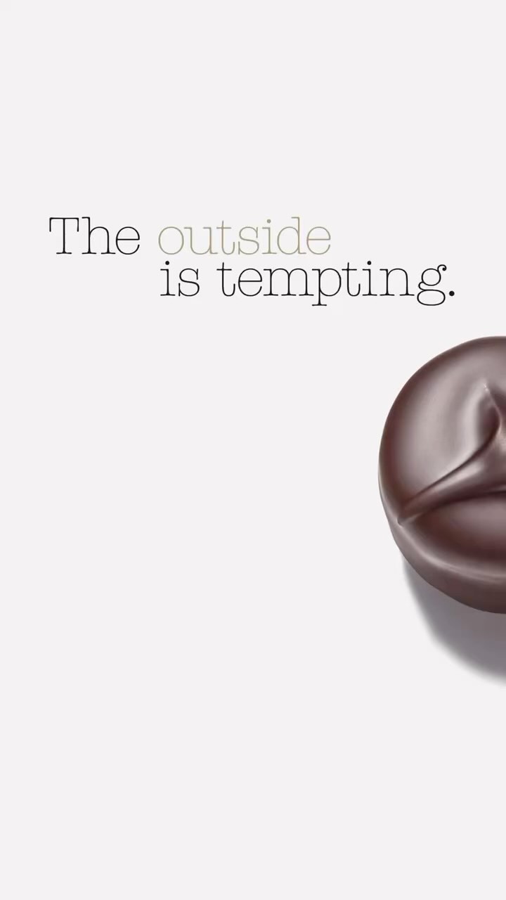 Dark chocolate candy on a white background with the text, 'The outside is tempting,' creating a tempting visual.