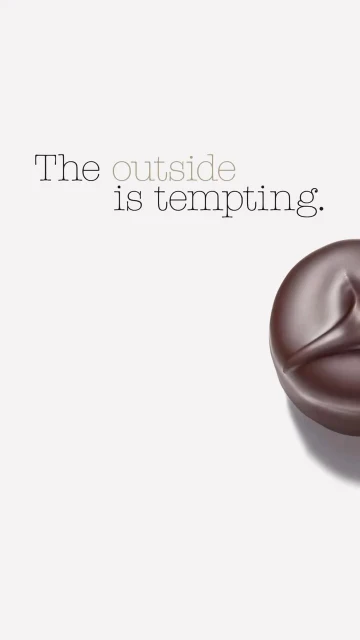 Dark chocolate candy on a white background with the text, 'The outside is tempting,' creating a tempting visual.