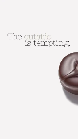 Dark chocolate candy on a white background with the text, 'The outside is tempting,' creating a tempting visual.