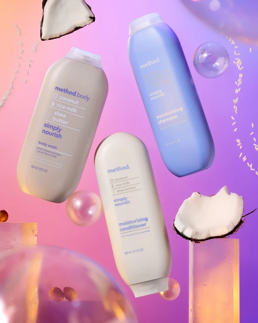 Three Method brand bottles of body wash, shampoo, and conditioner are displayed with coconuts and reflective spheres in a studio setting.