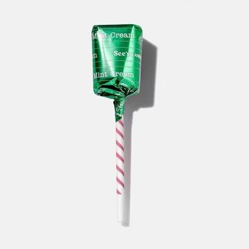Wrapped See's Candies Mint Cream lollipop with a white and pink striped stick on a white surface, offering a sweet confectionery treat.