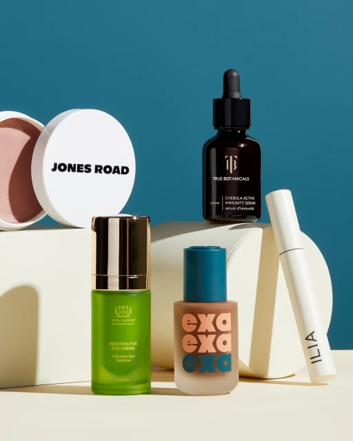 Several cosmetic containers including Jones Road, True Botanicals, and ILIA products are staged against a light-blue backdrop.