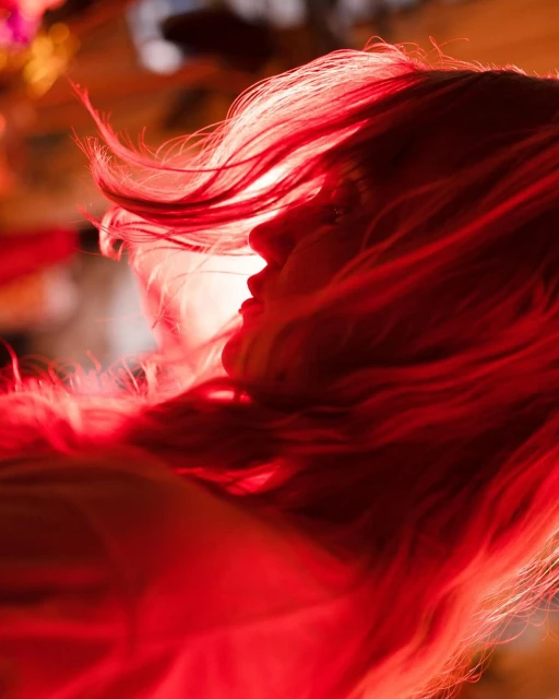 Portrait of an adult female with long red hair backlit in a photo studio, close up and shallow depth of field.