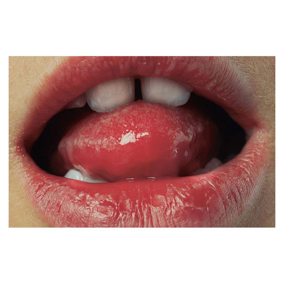Close-up studio shot of a young person's mouth showing the teeth, gums, and bright red tongue.