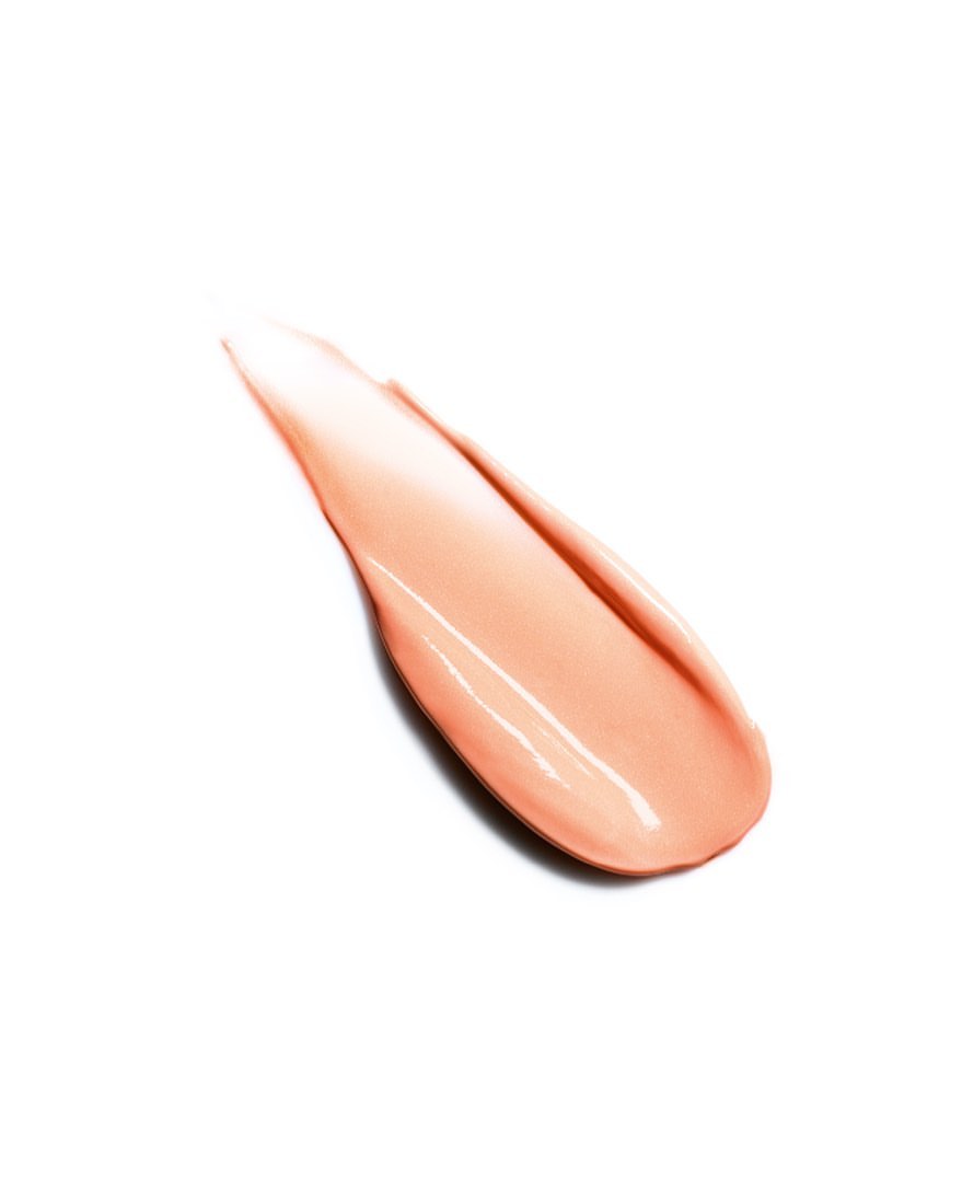 Close-up of a single swipe of shiny, peach-colored cosmetic cream against a clean white backdrop, showcasing its smooth texture.