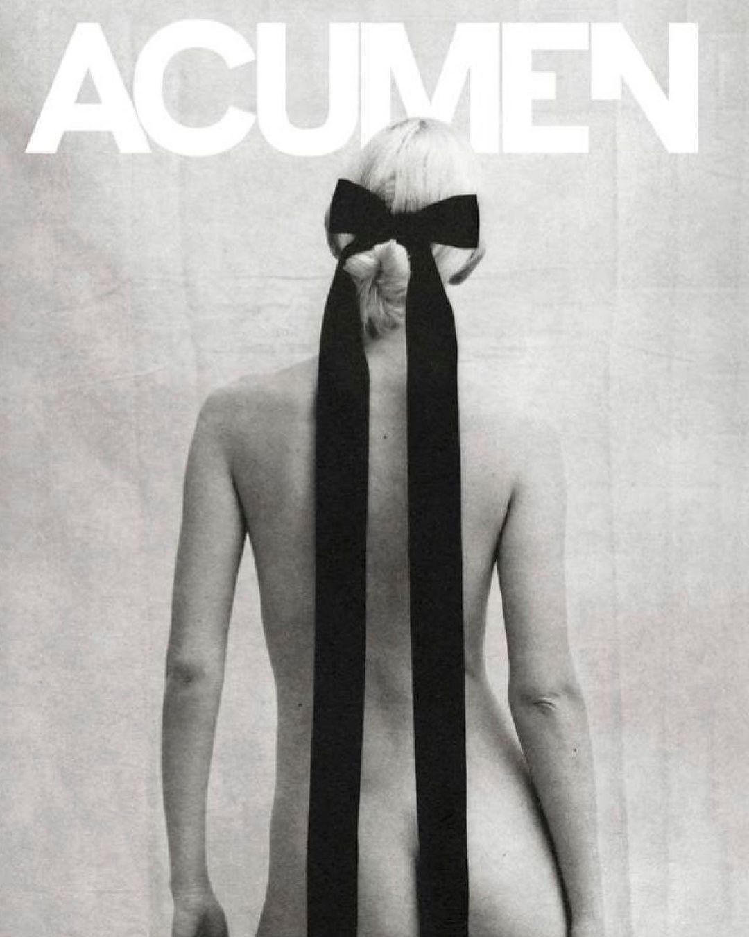 Back view of woman with blonde hair styled in a bow. Black and white, minimal composition with fashion and beauty elements.