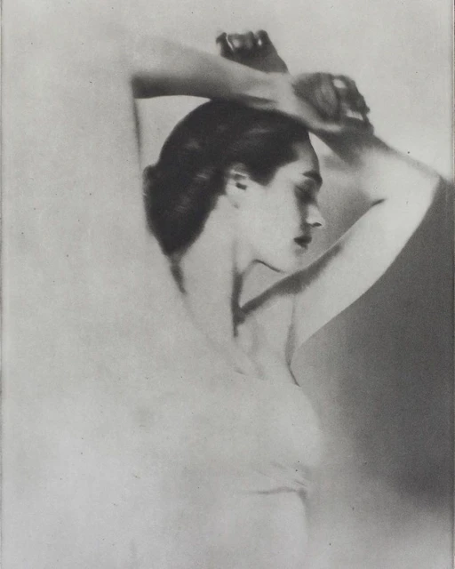 Monochrome portrait of a woman with arms raised behind her head, eyes closed, in a soft, high-key style. Close-up shows soft skin tones.