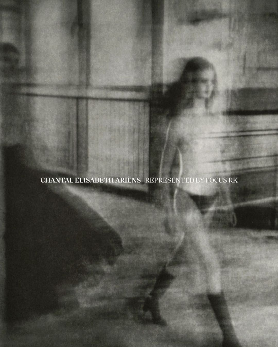 Blurred sepia-toned fashion shot of a woman walking, wearing knee-high boots. Studio with faded walls provides soft, filtered lighting.
