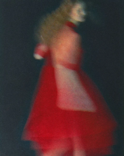 Abstract fashion photograph of a woman in a red dress, with long exposure blur and artistic motion creating a sense of dreamy movement.
