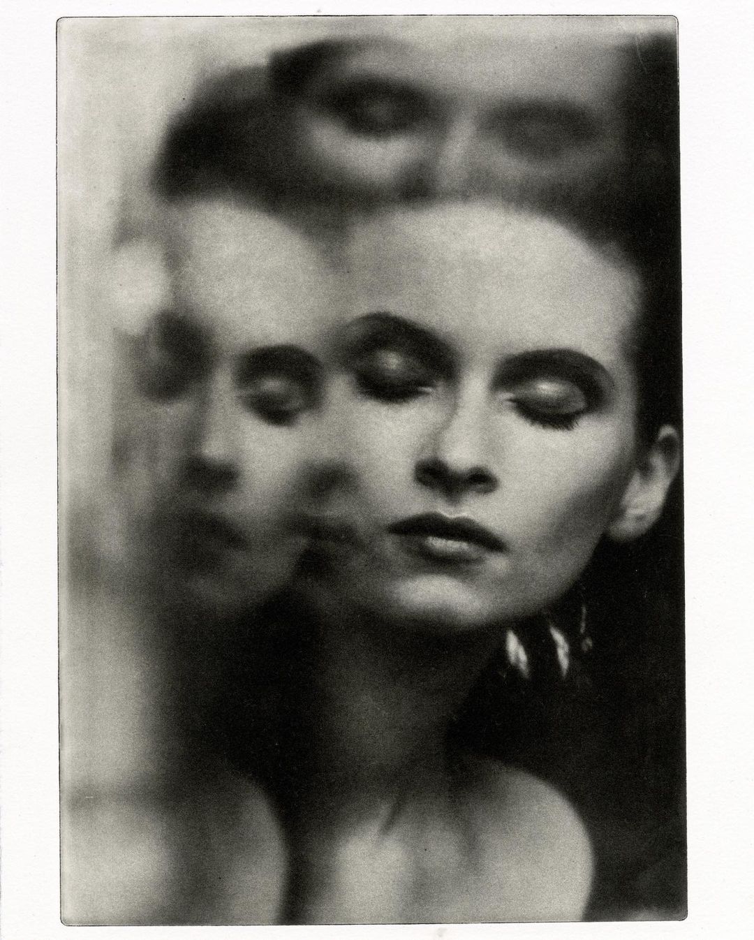 Black-and-white portrait of an adult woman with long dark hair, closed eyes, and statement earrings, with multiple exposed images.