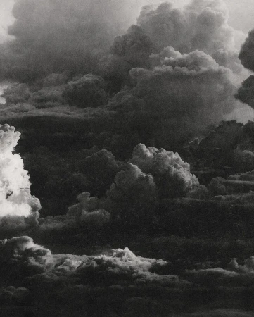 Dramatic black and white cloudscape with layered cloud formations filling the frame, creating a textured and atmospheric sky.