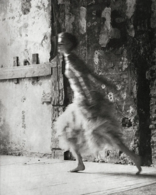 Blurred artistic photo of a woman in motion near a textured wall, showcasing motion blur, vintage style, and fine art photography.