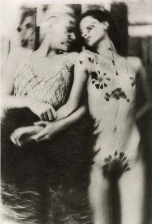 Monochrome photograph of two women in an indoor setting. One woman has dark body art. The photograph has soft focus and vintage effect.