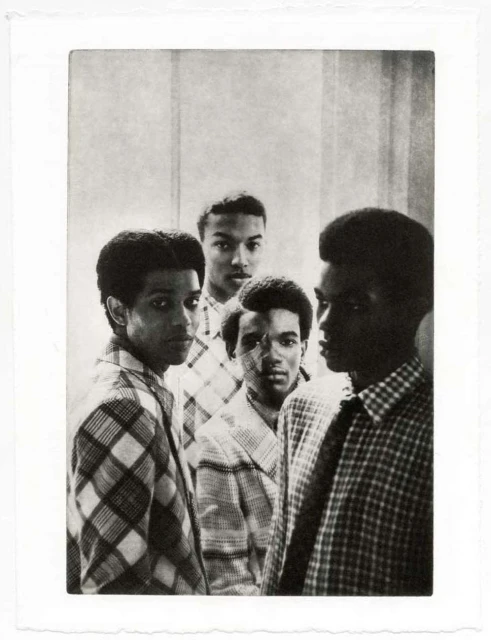 Black and white portrait of a group of young African American men wearing patterned shirts against a textured wall, fine art photography.