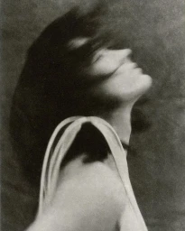 Close-up portrait of a woman with dark hair blowing across her face, head tilted back in motion by photographer Chantal Elisabeth Ariens.