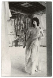 Model in textured patterned gown standing in a rustic interior with distressed walls, photographed by Chantal Elisabeth Ariens.