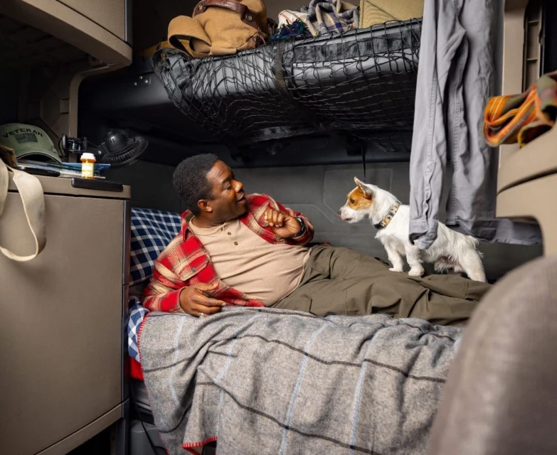 Man and Jack Russell Terrier resting in a truck cabin bed. Trucker relaxes with his dog in the sleeper berth of a semi-truck.