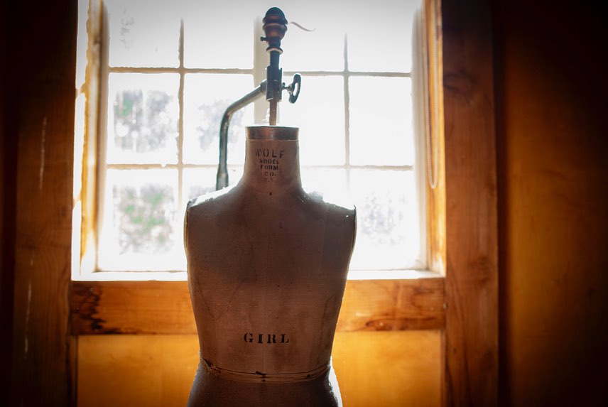 Vintage dress form in a room with window light. Rustic fashion industry, design, and tailoring concept. Antique mannequin display.