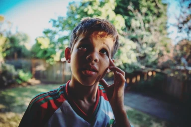 Young boy looking up thoughtfully wearing a striped sports jersey by photographer Charles Gullung.