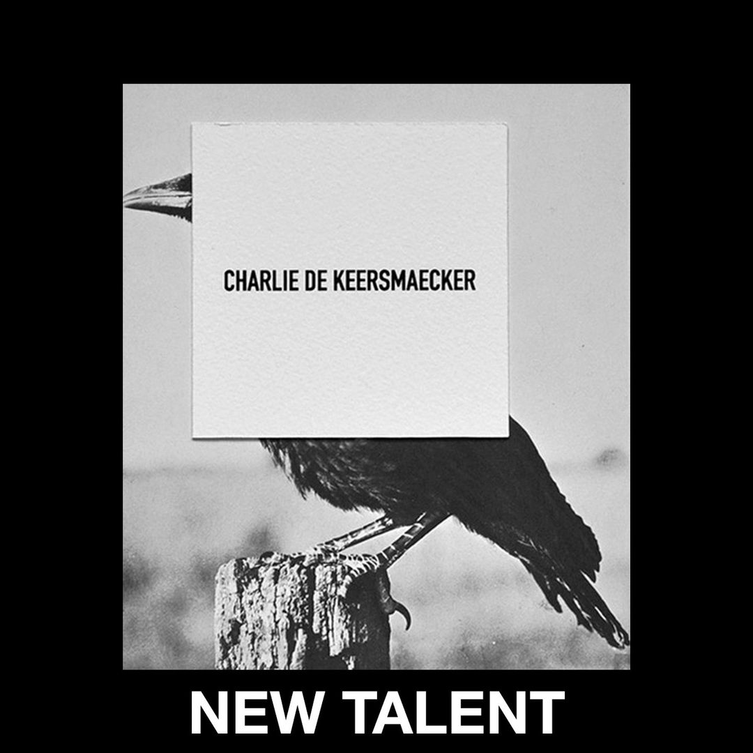 Monochrome image of a black crow perched on a wooden post with a white card overlaid, featuring the text 'Charlie De Keersmaecker'.