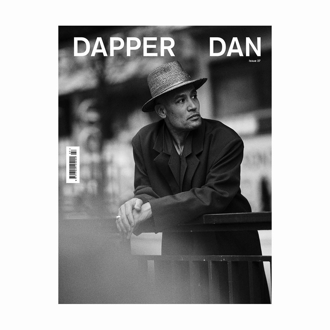 Black and white magazine cover featuring a man in a hat and coat leaning on a railing, looking to the right. Dapper Dan logo visible.