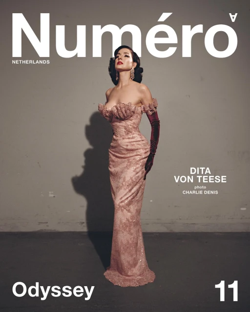 Dita Von Teese on the cover of Numéro Netherlands magazine in a pink gown with matching gloves against a grey backdrop.