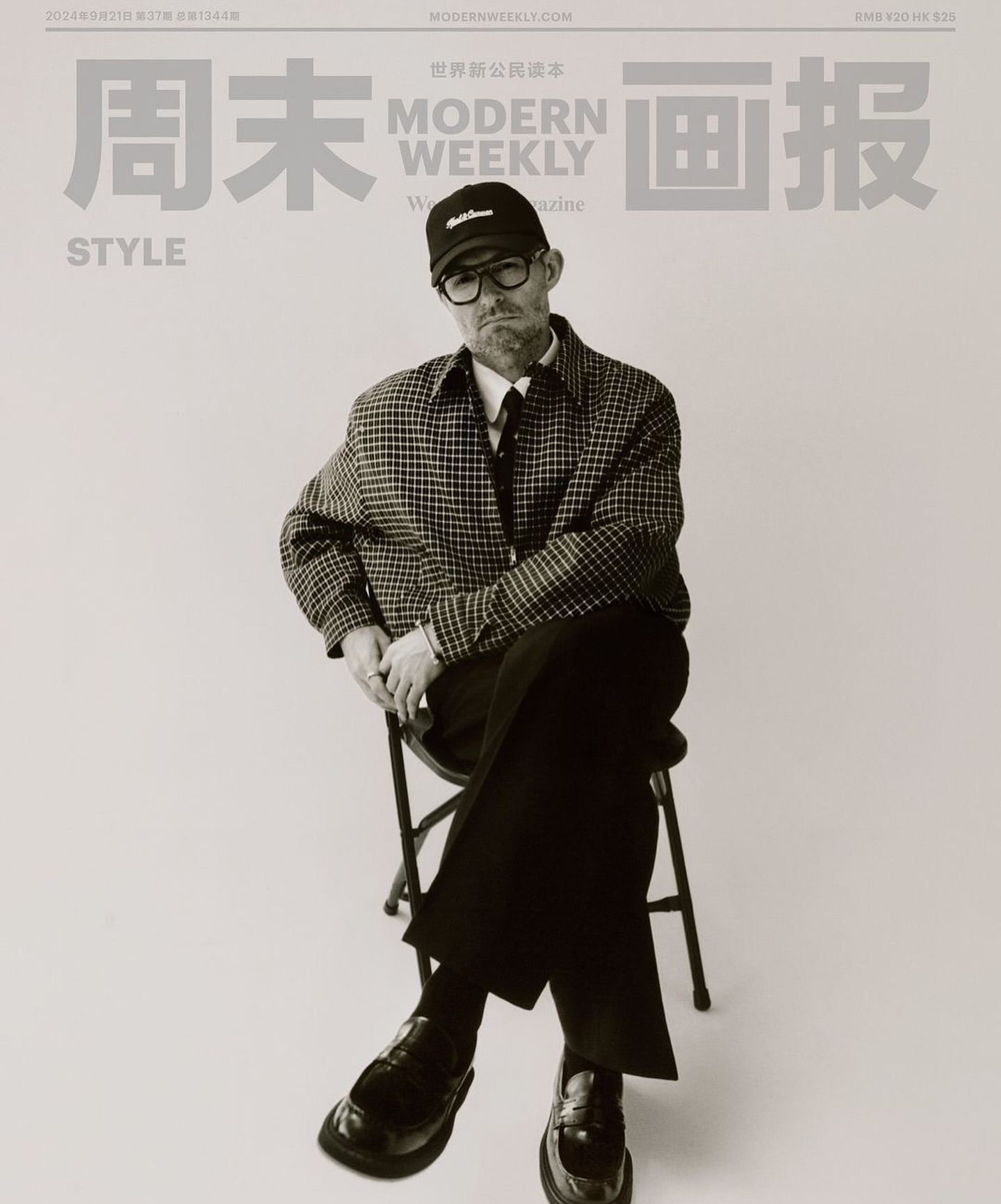 Modern Weekly magazine cover featuring an adult male wearing glasses, a cap, and a checkered jacket, seated on a metal stool.