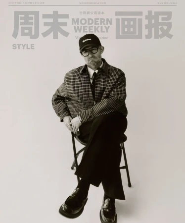 Modern Weekly magazine cover featuring an adult male wearing glasses, a cap, and a checkered jacket, seated on a metal stool.