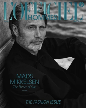 Magazine cover featuring Mads Mikkelsen in a close-up shot wearing a black jacket, against a textured background with the magazine title.