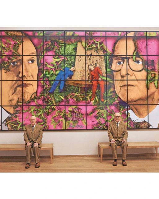 Two elderly men in suits seated before a large artwork featuring portraits and figures on benches amidst foliage and the text 'On the Bench'.