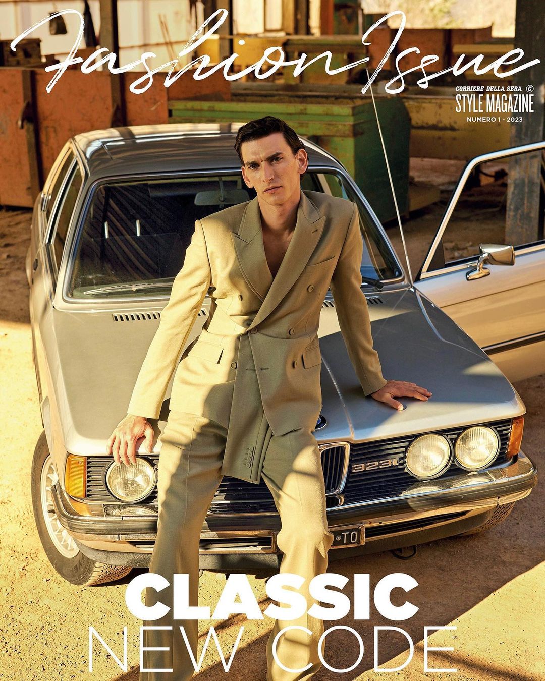 Fashion magazine cover featuring a man in a tan suit leaning against a silver car in an outdoor setting with a vintage aesthetic.