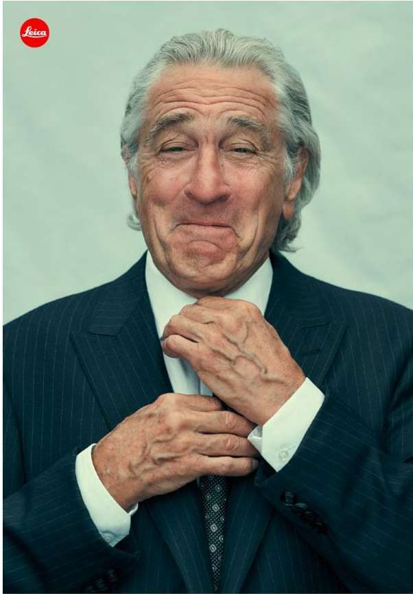 Portrait of mature man in suit, adjusting tie. Man has light skin, grey hair, and pleasant expression in studio shot.